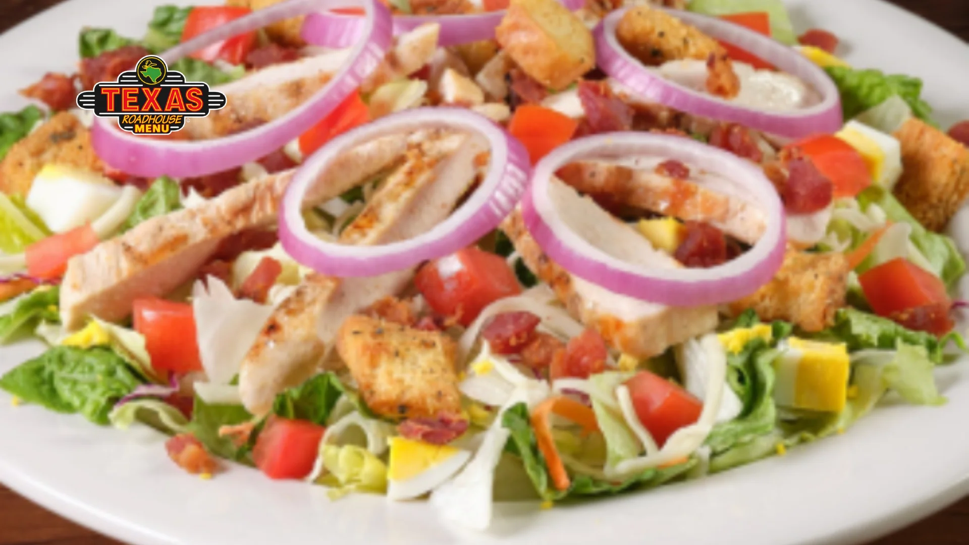 Grilled Chicken Salad is a plate full mixed with onions, marinated chicken, salad , egg, tomato.